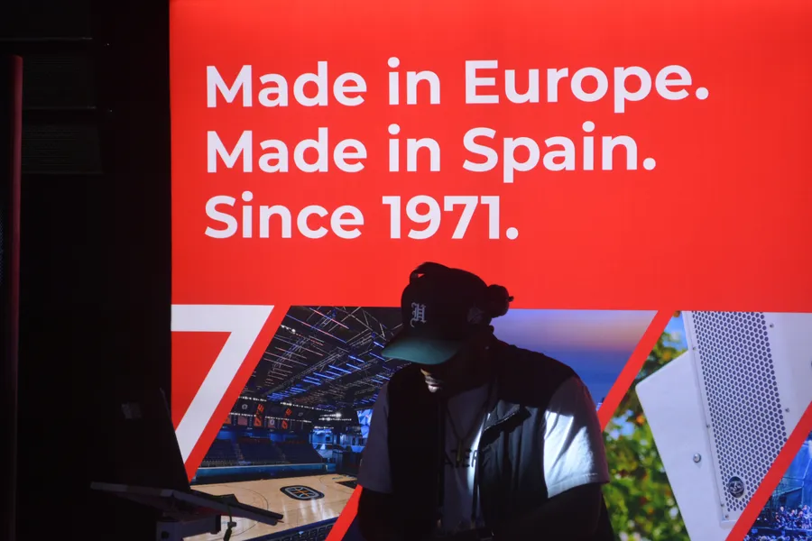 DJ backlit by a red stage banner at DJX